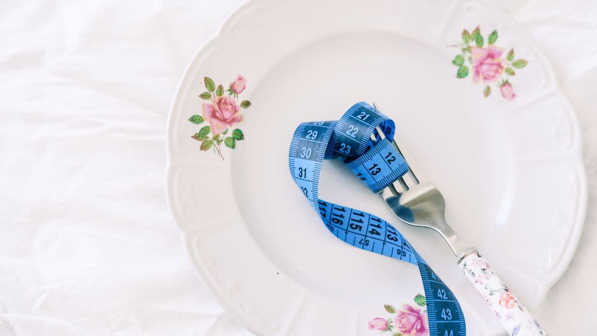 Plato vacío con una cinta métrica enrollada en un tenedor