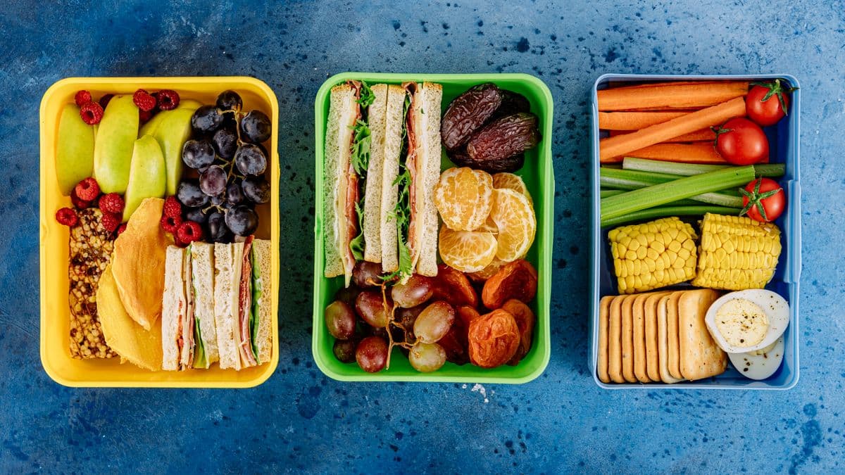 Tres tuppers con comida equilibrada: fruta, sándwiches, verduras y proteína